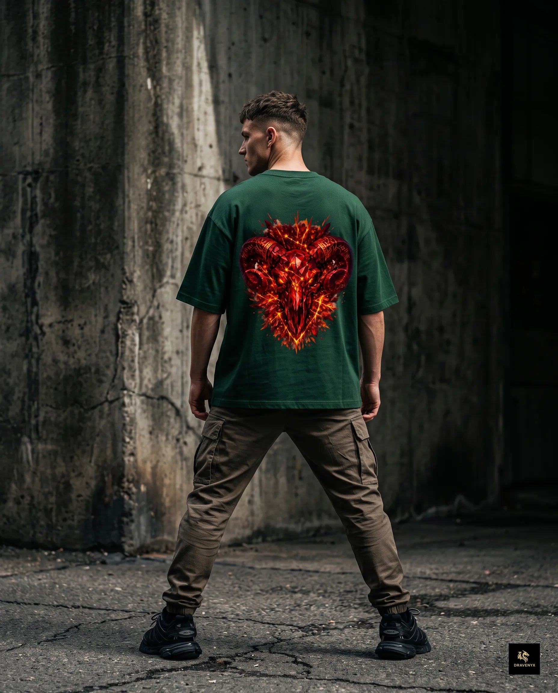DRAVENYX® Aries Infernal Ram Oversized Tee in Bottle Green — front view featuring left-chest crystalline Aries wing-mark emblem in molten amber and iron tones — back view showing full DTF print of infernal crystal ram skull with rune-inscribed curling horns and golden ember burst