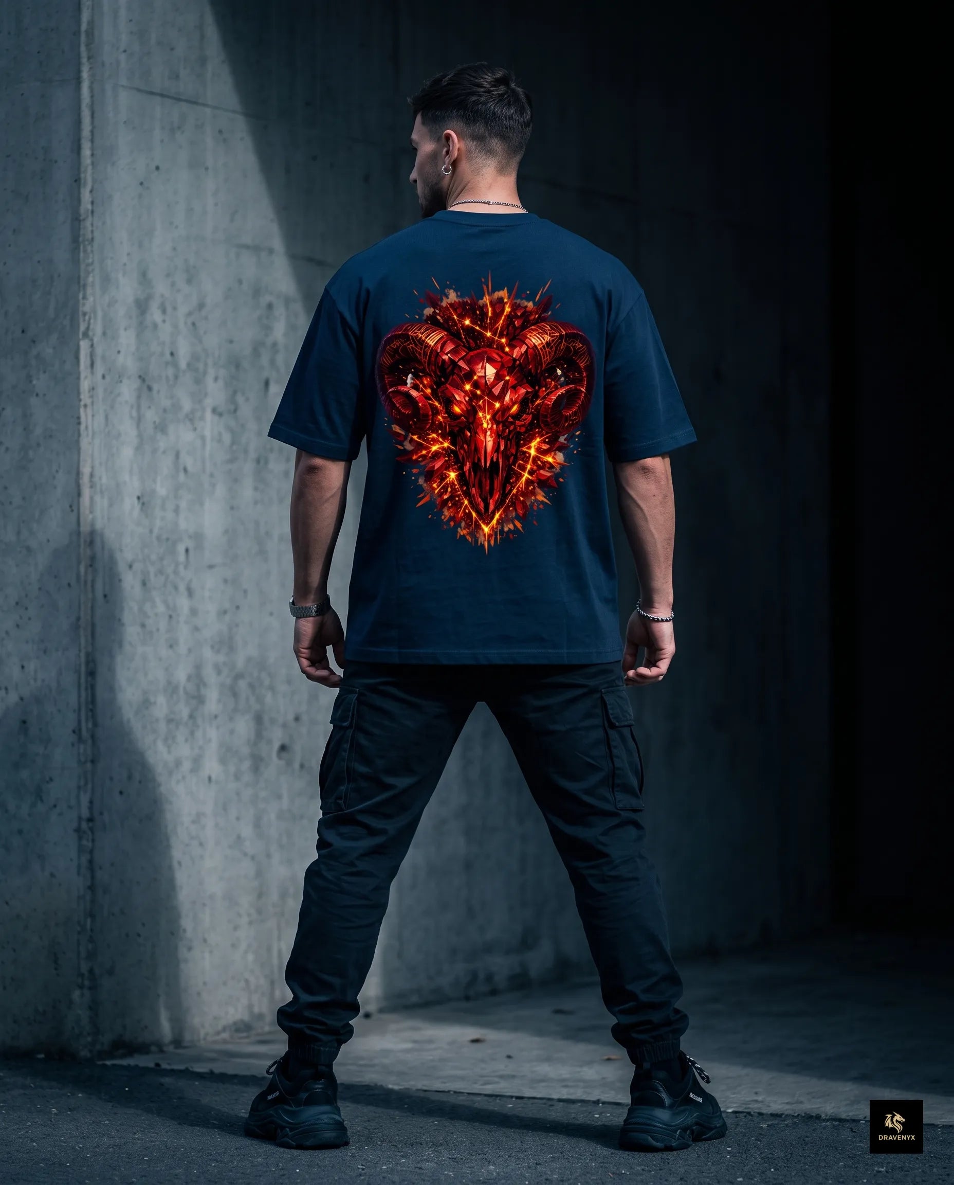 DRAVENYX® Aries Infernal Ram Oversized Tee in Navy Blue — front view featuring left-chest crystalline Aries wing-mark emblem in molten amber and iron tones — back view showing full DTF print of infernal crystal ram skull with rune-inscribed curling horns and golden ember burst