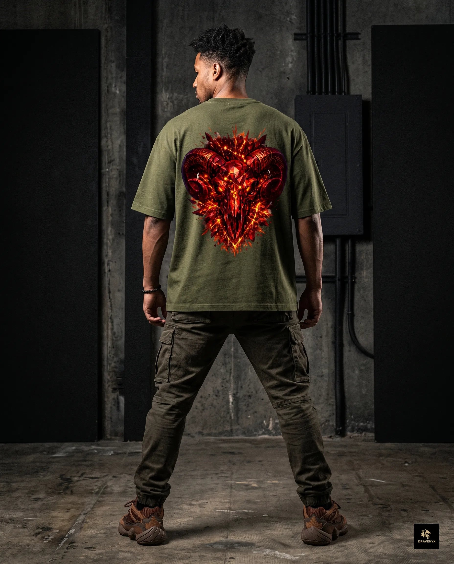 DRAVENYX® Aries Infernal Ram Oversized Tee in Olive Green — front view featuring left-chest crystalline Aries wing-mark emblem in molten amber and iron tones — back view showing full DTF print of infernal crystal ram skull with rune-inscribed curling horns and golden ember burst