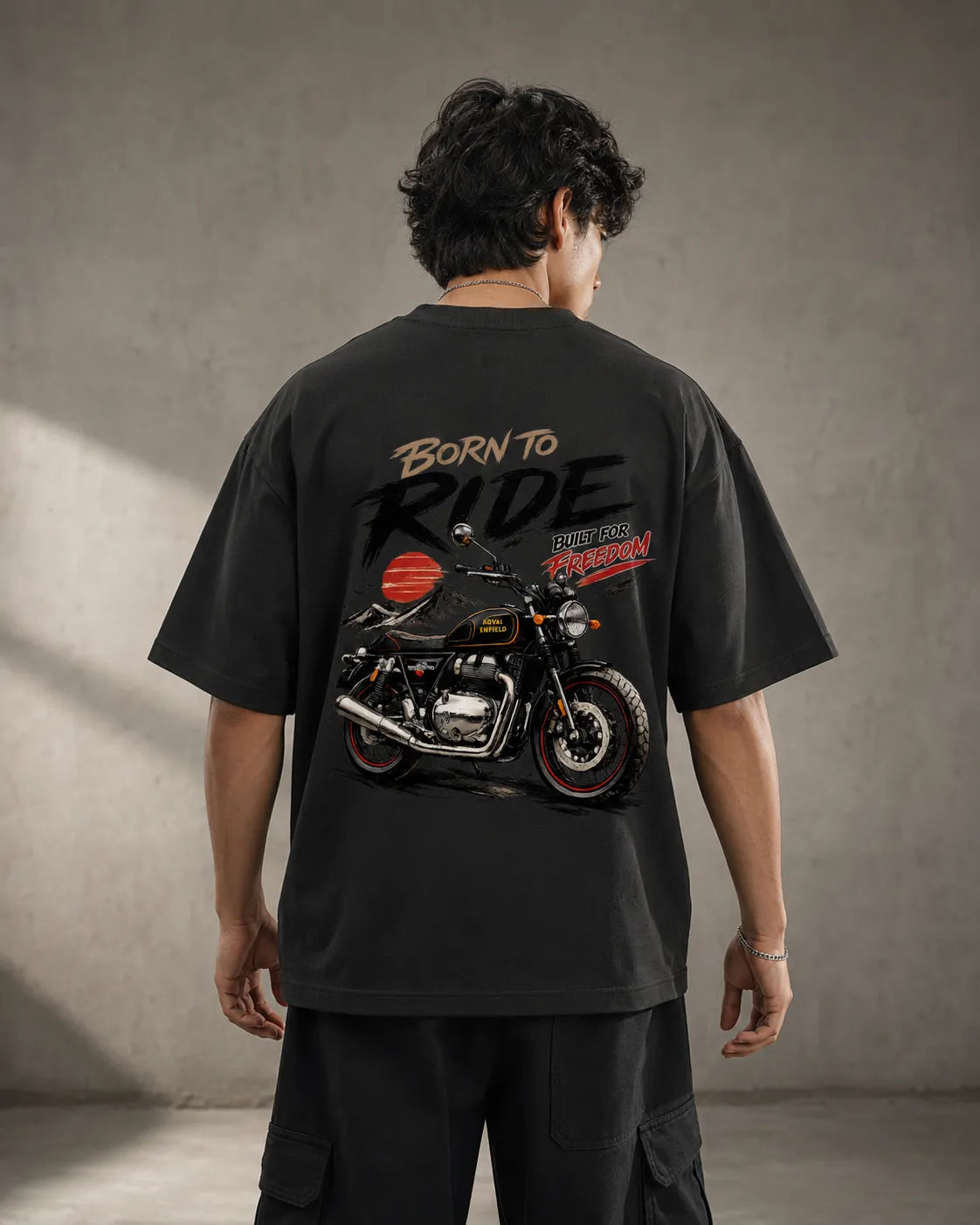 DRAVENYX® Born To Ride oversized tee in Black — front view showing left chest moto-badge print and drop-shoulder silhouette — back view with full-panel moto-art graphic and 'Born To Ride / Built For Freedom' DTF print