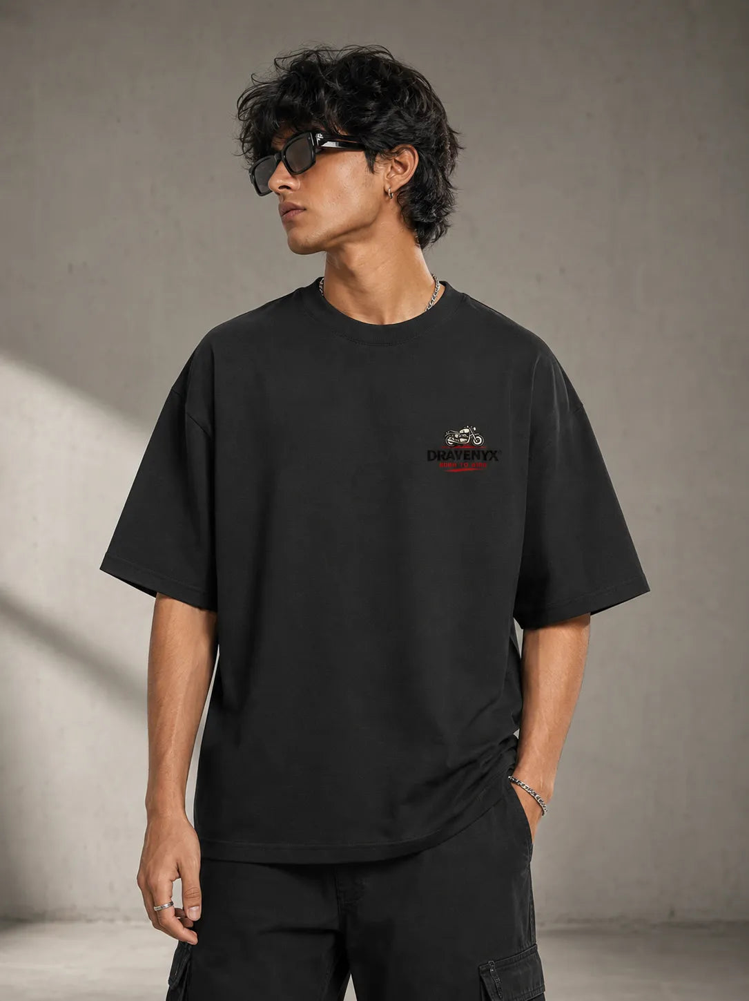 DRAVENYX® Born To Ride oversized tee in Black — front view showing left chest moto-badge print and drop-shoulder silhouette — back view with full-panel moto-art graphic and 'Born To Ride / Built For Freedom' DTF print