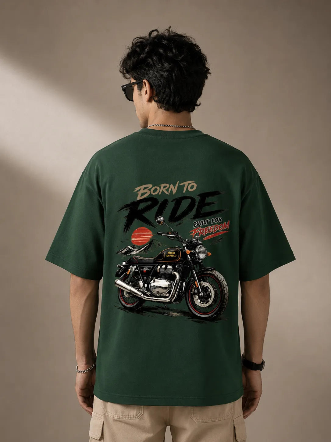 DRAVENYX® Born To Ride oversized tee in Bottle Green — front view showing left chest moto-badge print and drop-shoulder silhouette — back view with full-panel moto-art graphic and 'Born To Ride / Built For Freedom' DTF print