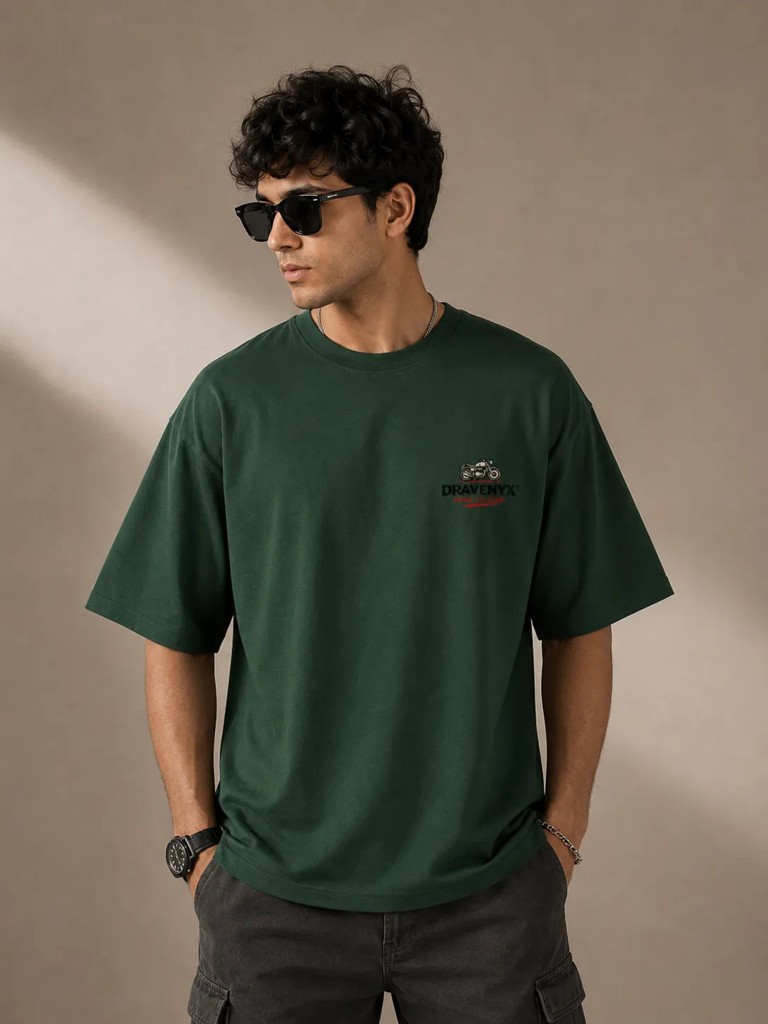 DRAVENYX® Born To Ride oversized tee in Bottle Green — front view showing left chest moto-badge print and drop-shoulder silhouette — back view with full-panel moto-art graphic and 'Born To Ride / Built For Freedom' DTF print