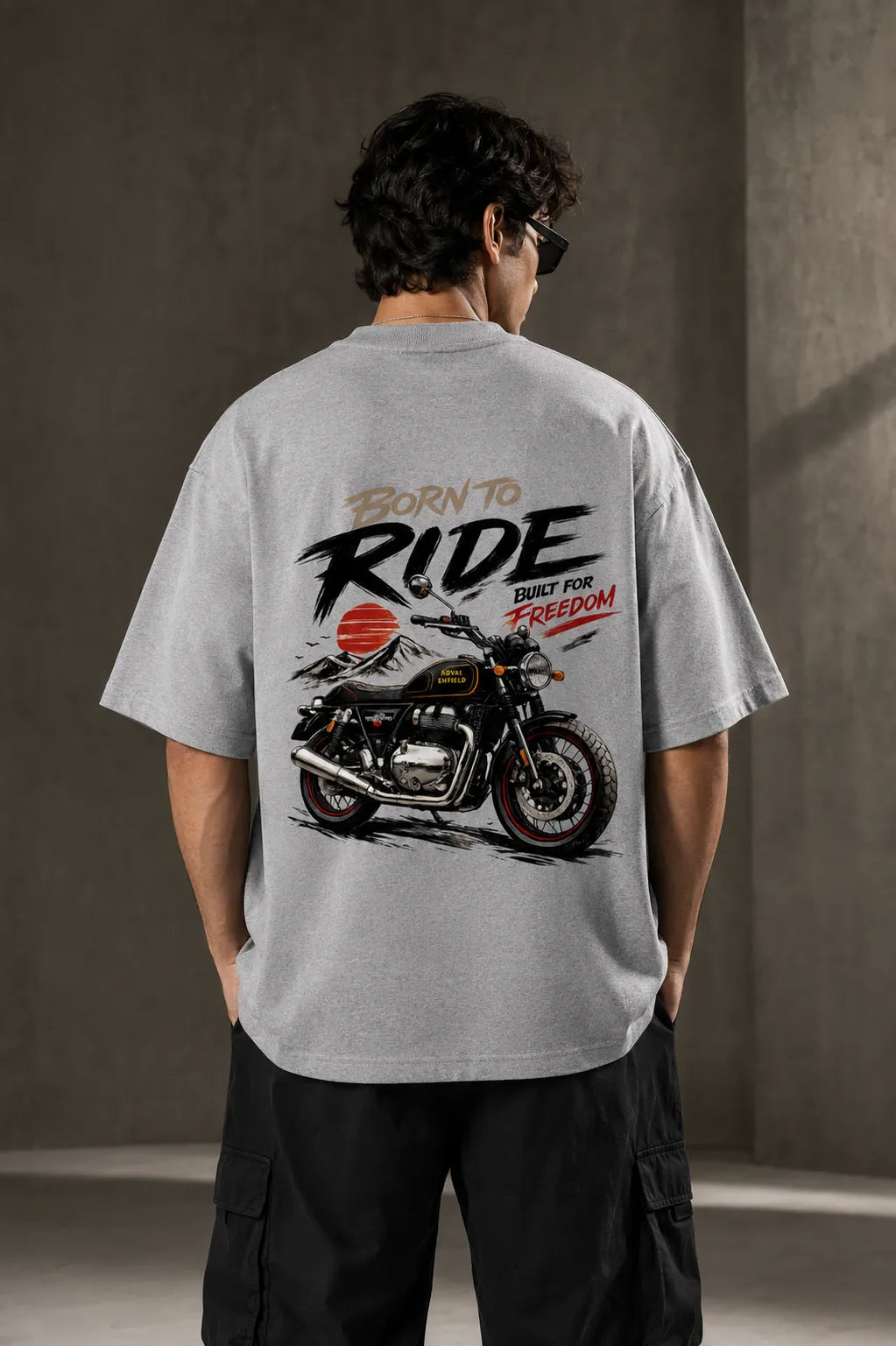 DRAVENYX® Born To Ride oversized tee in Grey Melange — front view showing left chest moto-badge print and drop-shoulder silhouette — back view with full-panel moto-art graphic and 'Born To Ride / Built For Freedom' DTF print
