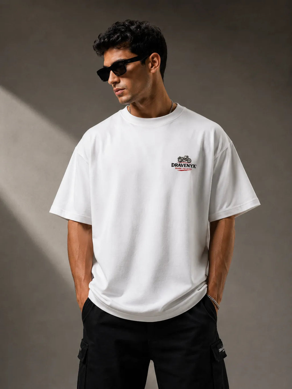 DRAVENYX® Born To Ride oversized tee in White — front view showing left chest moto-badge print and drop-shoulder silhouette — back view with full-panel moto-art graphic and 'Born To Ride / Built For Freedom' DTF print